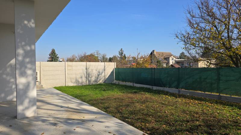 Der Garten eines Einfamilienhauses in Piešťany mit Rasen, Betonterrasse und Umzäunung.