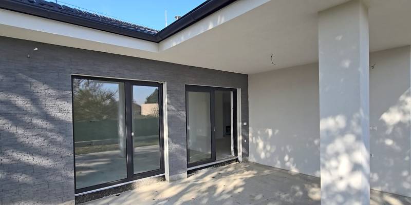 Die Terrasse eines Einfamilienhauses in Piešťany mit großen verglasten Türen und grauen Wänden.