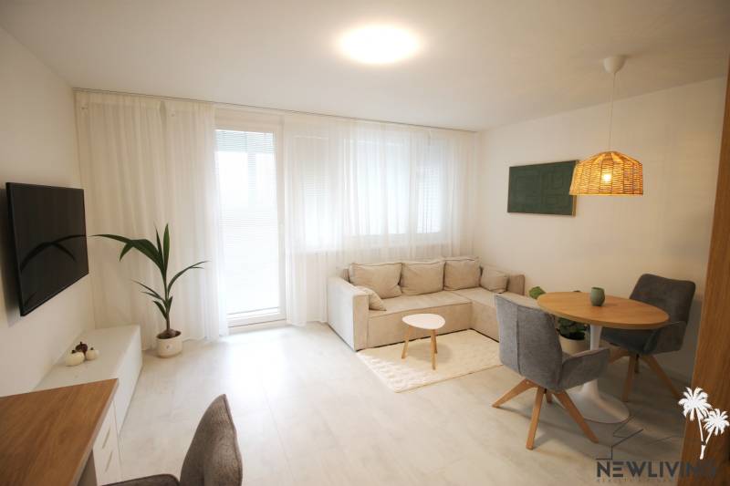 Geräumiges Wohnzimmer mit bequemer Couch, Boden mit Holzdekor, Esstisch.