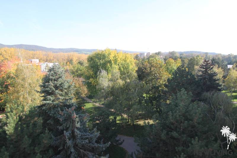 Blick von der Straße Valová in Piešťany mit dichtem Grün und sanften Hügeln im Hintergrund.
