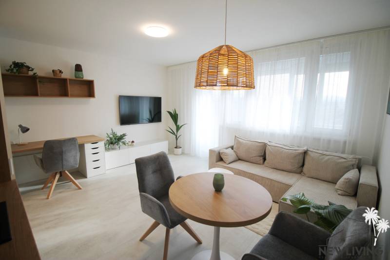 Helles Wohnzimmer mit Sofa, Couchtisch, Arbeitsecke und Holzboden.