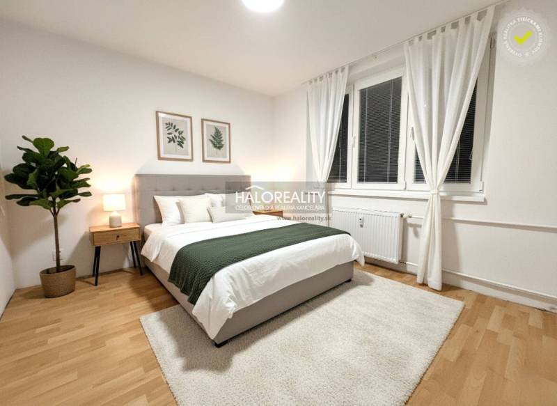 Helles Schlafzimmer in einer Zweizimmerwohnung mit Holzboden, Dekoration und großem Fenster.