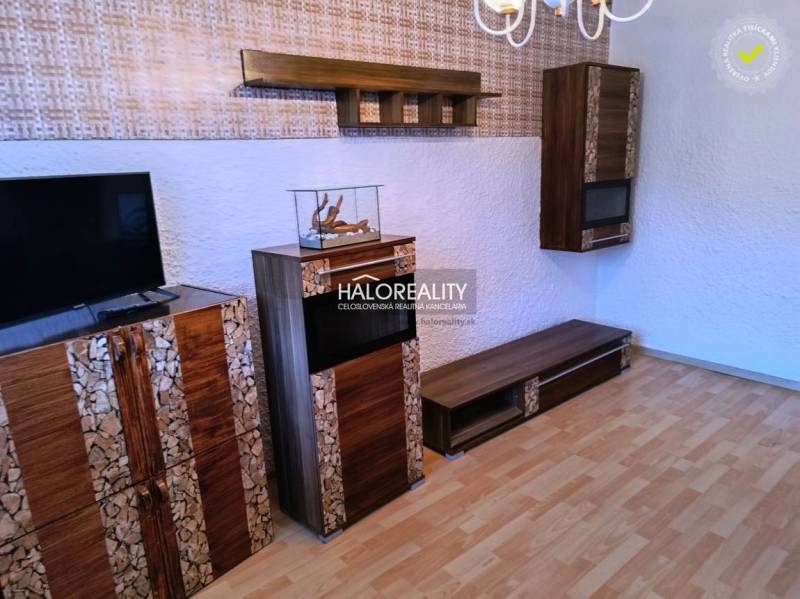 Wohnzimmer in einer 3-Zimmer-Wohnung mit Fernseher und Holzboden.