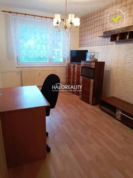 Ein Zimmer mit einem Holzboden, einem Büroschreibtisch und Regalen in einer 3-Zimmer-Wohnung.