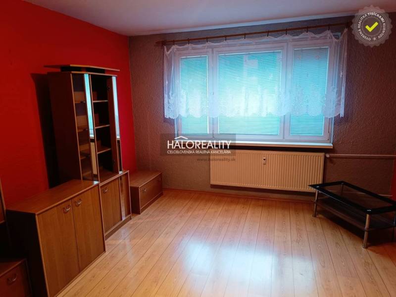 Ein Zimmer mit Holzboden, roten Wänden und Möbeln in einer 3-Zimmer-Wohnung.