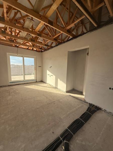 Innenraum eines Einfamilienhauses mit freiliegenden Deckenbalken und vorbereiteter Elektroinstallation.