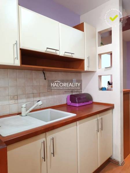 Küchenecke in einem Einzimmerapartment mit Spüle und Schränken.