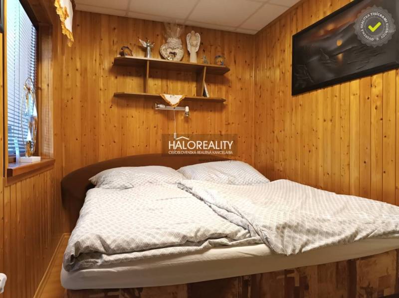 Schlafzimmer in der Hütte mit Holzwand und Regalen über dem Bett.