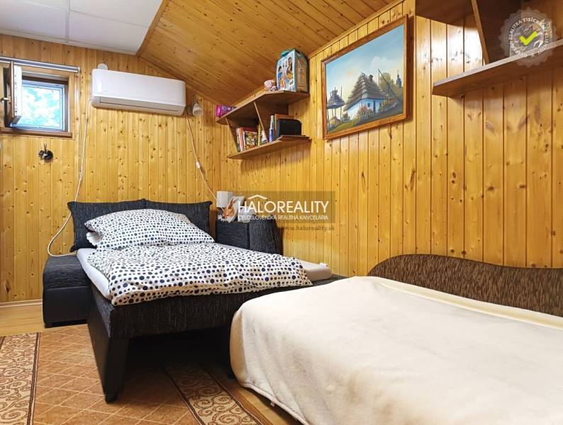 Ein Zimmer in einer Hütte mit Holzwandverkleidung und einem bequemen Bett.
