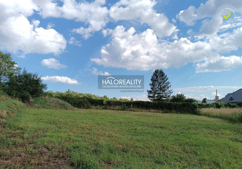 Ein Baugrundstück in Čerhov mit Grünflächen, Bäumen und einem Himmel mit Wolken.