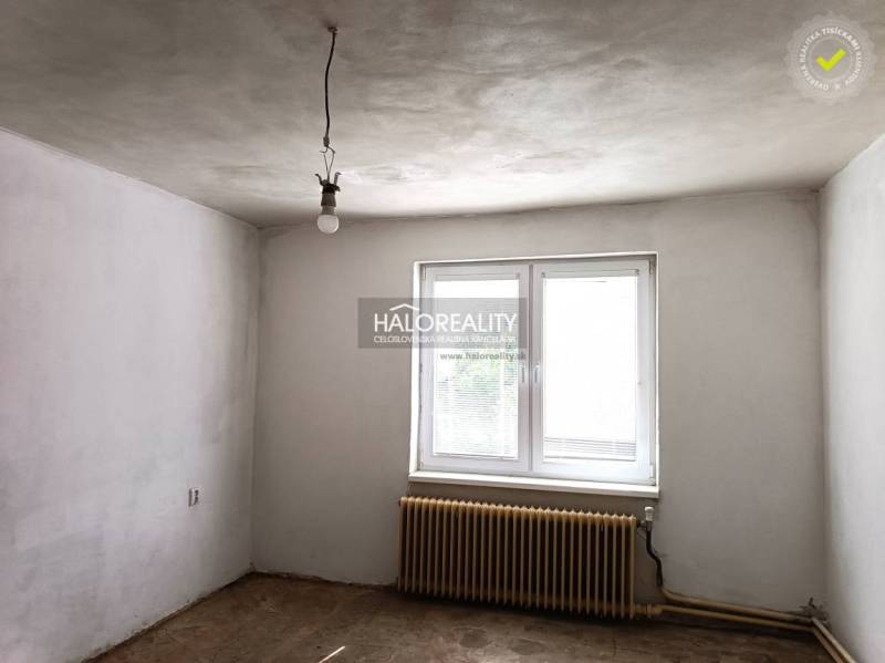 Ein leerer Raum in einem Einfamilienhaus mit weißen Wänden, einem Heizkörper und einem Fenster.