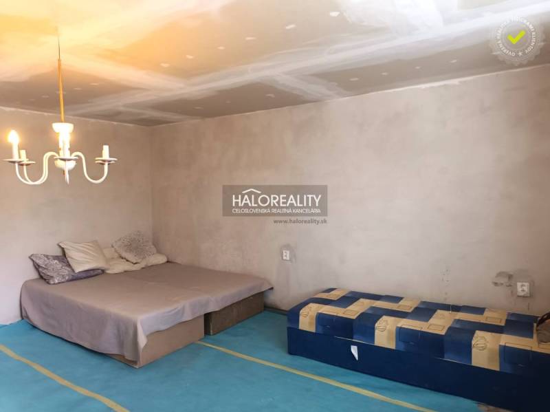 Ein Schlafzimmer in einem Einfamilienhaus mit Bett, Matratze, Leuchte und einfacher Möbel.