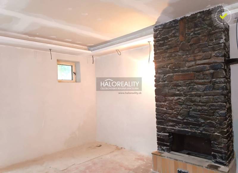 Interieur eines Einfamilienhauses mit einem Steinkamin und einem kleinen Fenster.