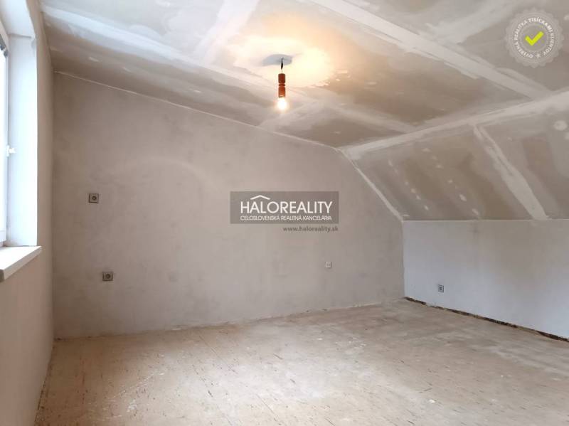 Unfertiger Dachbodenraum in einem Einfamilienhaus, helle Wände und Holzboden.