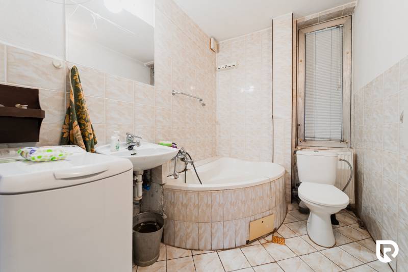 Badezimmer mit Badewanne, Waschbecken und Waschmaschine in einem Einfamilienhaus.