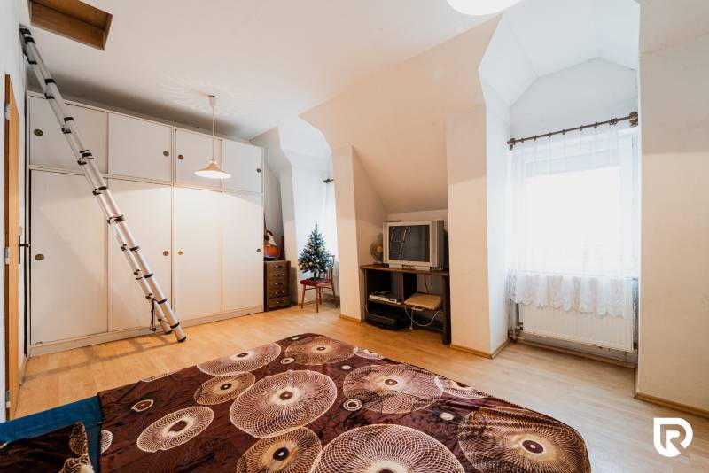 Ein Zimmer in einem Einfamilienhaus mit einem Holzboden, einem Fernseher und einem Schrank.