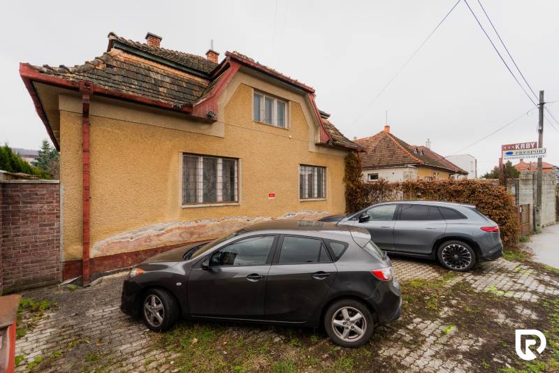 Ein Einfamilienhaus in der Partizánska-Straße in Bánovce nad Bebravou mit zwei Autos, die davor geparkt sind.