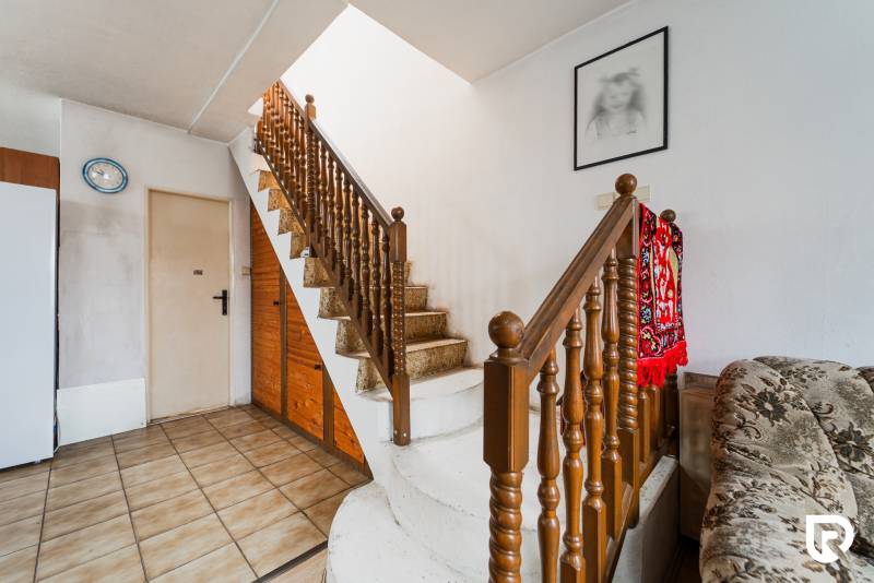 Das Innere eines Einfamilienhauses mit einer Treppe, einem tiefroten Teppich und einem Bild an der Wand.