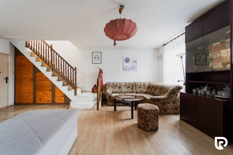 Wohnzimmer in einem Einfamilienhaus mit Holztreppe, Sofa, Schrank und Boden mit Holzdekor.