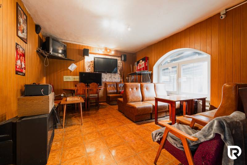 Innenraum eines Einfamilienhauses mit Ledersofas, Holzvertäfelung und Fernsehern.