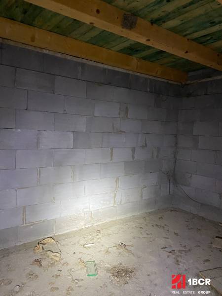 Ein roher Raum in einer Hütte mit Betonwänden und einer Holzdecke.