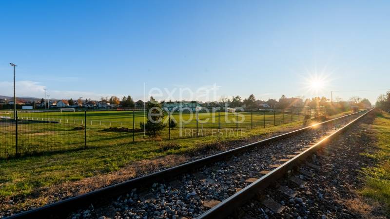 Die Eisenbahnstrecke bei Sonnenuntergang in Lozorno an der Borovicová, umgeben von grünen Wohngebieten.