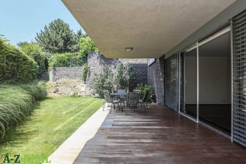 Terrasse mit Holzboden, Gartenmöbeln und Grünflächen bei einer 3-Zimmer-Wohnung.