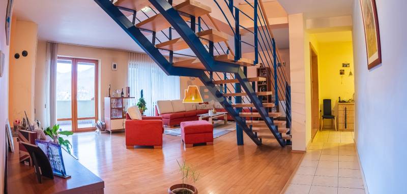 Innenraum der Villa mit Holzboden, Treppe und rotem Sofa.