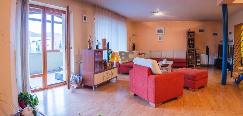 Wohnzimmer in einer Villa mit rotem Sofa und Boden in Holzoptik.