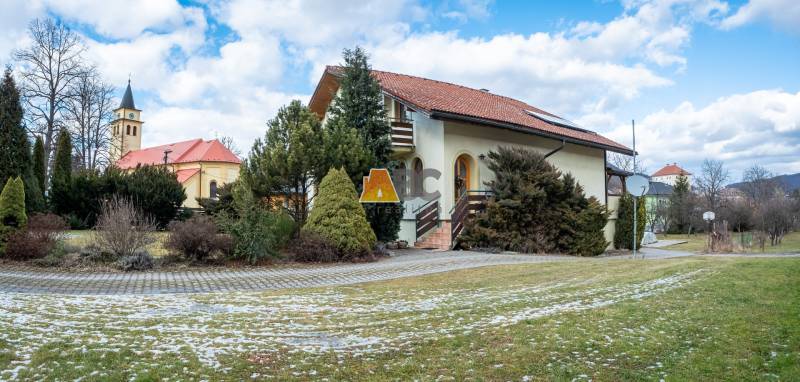 Eine Villa in der Andrej-Sládkovič-Straße in Žarnovica, umgeben von Grün, mit einer Kirche im Hintergrund.