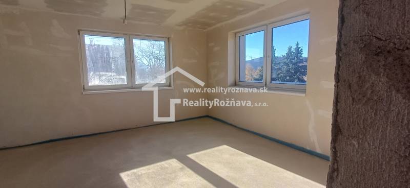 Das Innere eines Einfamilienhauses mit hellem Boden und großen Fenstern für ausreichend Licht.