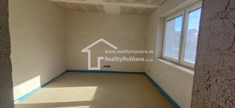 Ein leerer Raum in einem Einfamilienhaus mit einem Fenster und unvollendeten Wänden.