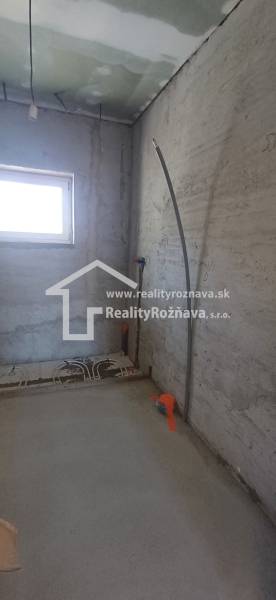 Innenraum eines im Bau befindlichen Einfamilienhauses mit Fenster und Vorbereitung für die Installation von Leitungen.