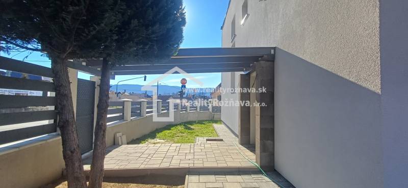 Der Hof des Einfamilienhauses in der Košická Straße in Rožňava mit einem Holzzaun und einem Baum.