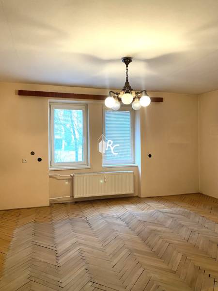 Ein Zimmer in einer 2-Zimmer-Wohnung mit einem Holzboden und einem hängenden Kronleuchter.