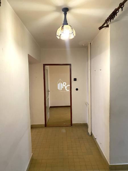 Ein Flur mit Fliesen und einem Kronleuchter, der zu einem Raum in einer Zweizimmerwohnung führt.