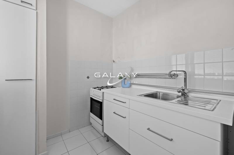 Küche in einer Einzimmerwohnung mit weißer Küchenzeile und Herd.