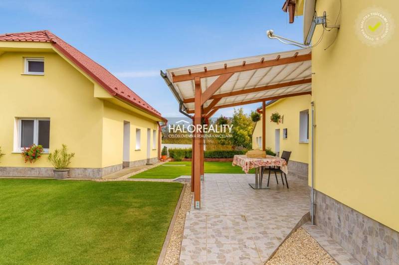 Ein Garten bei einem Einfamilienhaus in Beša mit einer Terrasse und gepflegtem Rasen.