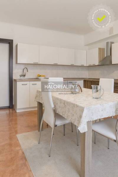 Eine Küche in einem Einfamilienhaus mit einer weißen Küchenzeile und einem Esstisch mit vier Stühlen.