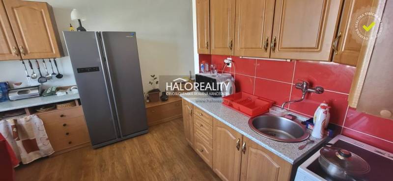 Küche in einer Einzimmerwohnung mit Holzschränken, roten Fliesen und einem großen Kühlschrank.