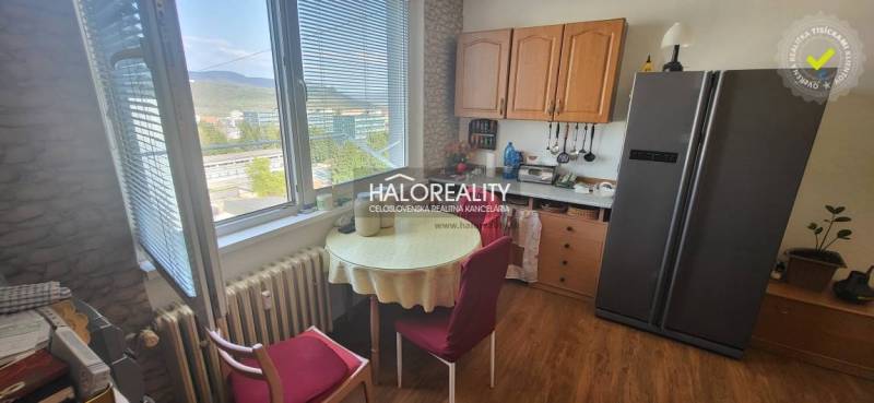 Küche in einer Einzimmerwohnung mit Tisch, Stühlen und Blick aus dem Fenster.