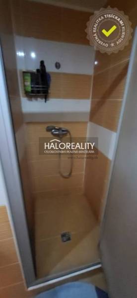 Duschkabine in einer Einzimmerwohnung mit orangefarbenen Fliesen und Stauraum an der Wand.