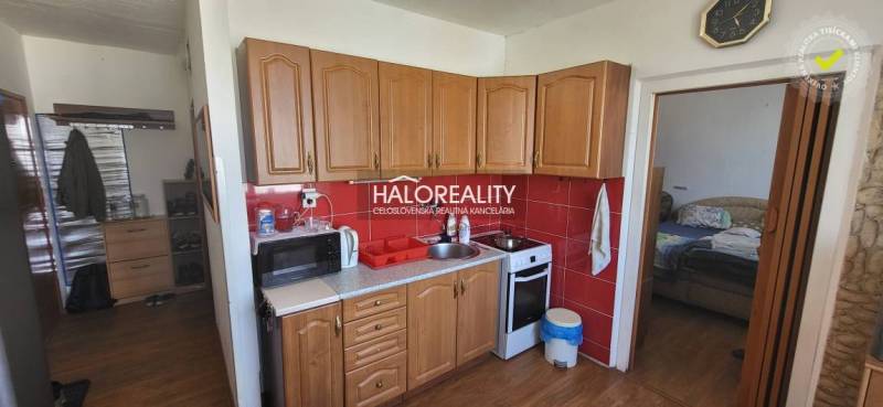 Küche in einer Einzimmerwohnung mit Holzschränken, Mikrowelle und Herd.