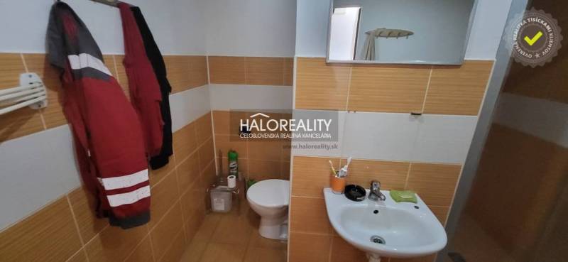 Badezimmer mit Toilette und Waschbecken in einer Einzimmerwohnung mit Fliesen in warmen Tönen.