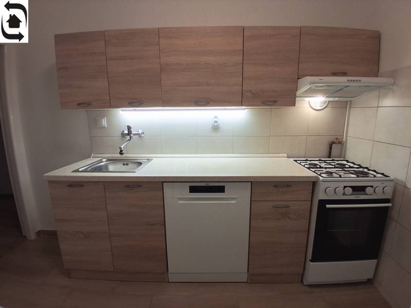 Küche mit Holzelementen, Spüle, Geschirrspüler und Herd in einer 3-Zimmer-Wohnung.