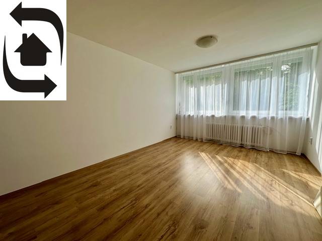 Ein heller Raum mit Holzboden und einem großen Fenster in einer 3-Zimmer-Wohnung.