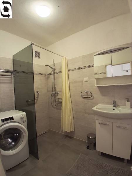 Badezimmer mit Duschkabine, Waschmaschine und Spiegelschrank in einer 3-Zimmer-Wohnung.