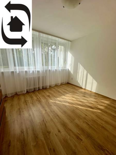 Ein Zimmer in einer 3-Zimmer-Wohnung mit einem Holzboden und einem großen Fenster.