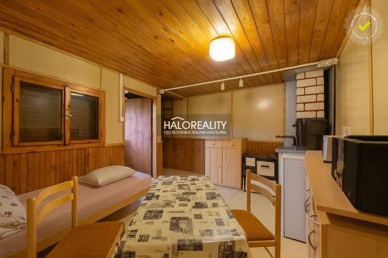 Innenraum mit Tisch, Stühlen und einem Sessel mit Stoffbezug, Boden mit Holzdekor.