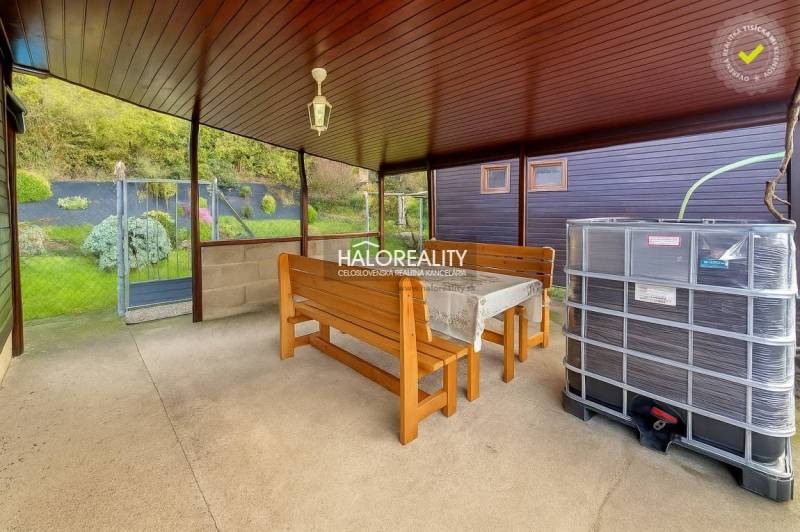 Überdachte Terrasse mit Tisch, Bänken und Blick auf die Gärten in Bytča.